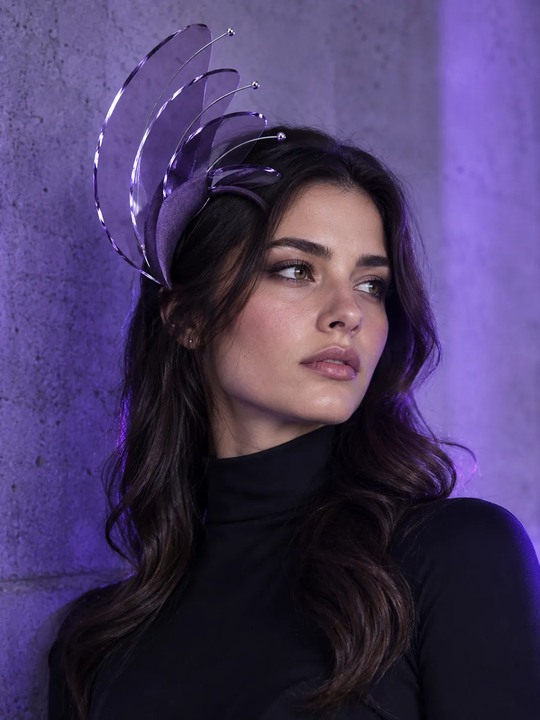 A woman wearing the Buttress headpiece against a concrete wall